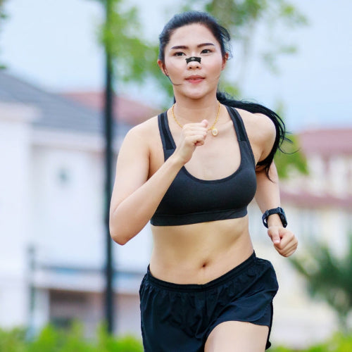 Woman in athletic wear running outdoors with a blurred background